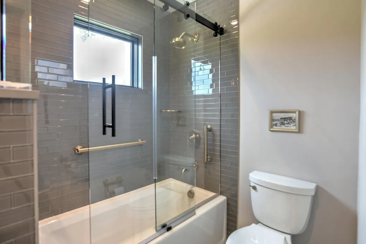 A serene, modern bathroom featuring a glass shower enclosure, a sleek bathtub, and contemporary fixtures. The space is accented with a small framed picture and exudes a spa-like atmosphere ideal for relaxation and self-care.